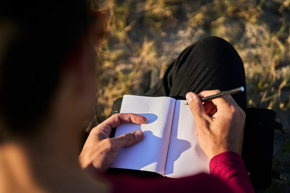 A person is holding a pen over a white book.